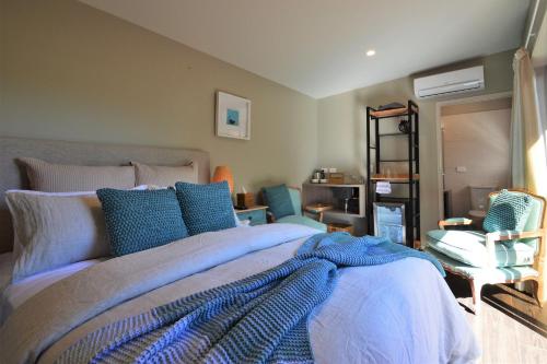 um quarto com uma cama grande e almofadas azuis em BeachBox Boutique Accommodation em Coopers Beach