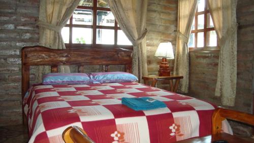 1 dormitorio con 1 cama con manta roja y blanca en EL DESCANSO “the Rest”, en Otavalo
