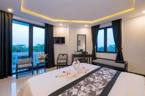 a bedroom with a bed with two swans on it at Hoianation Villas Hotel in Hoi An
