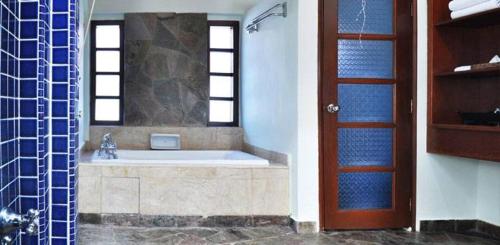 a bathroom with a tub and a shower with a window at Avillion Port Dickson in Port Dickson