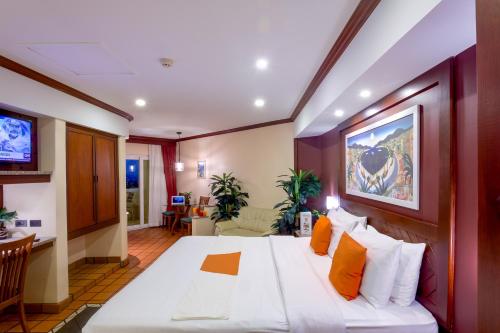 1 dormitorio con 1 cama blanca grande con almohadas de color naranja en Pacific Club Resort, en Karon Beach