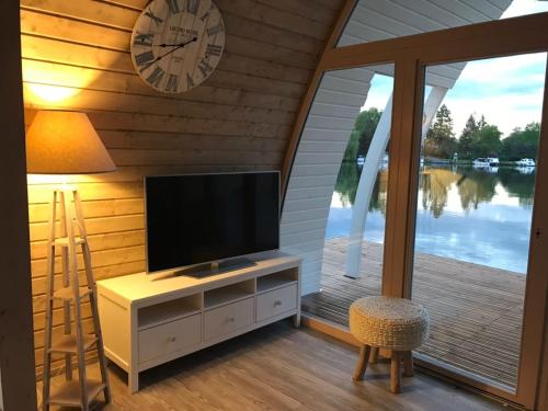 a living room with a television and a clock on the wall at schwimmendes Seehotel in Parey