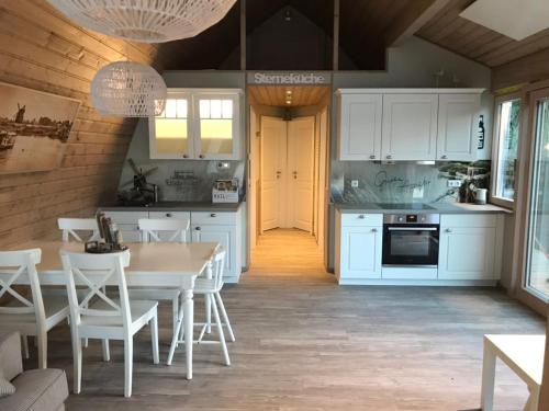 a kitchen with white cabinets and a table and chairs at schwimmendes Seehotel in Parey