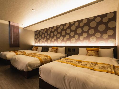 a hotel room with two beds and a wall at GRAND BASE Beppu Ekimae in Beppu