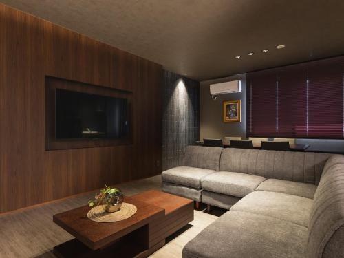 a living room with a couch and a tv at GRAND BASE Beppu Ekimae in Beppu