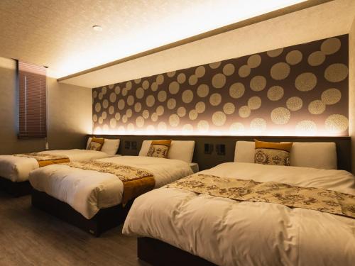 two beds in a room with twothirds at GRAND BASE Beppu Ekimae in Beppu