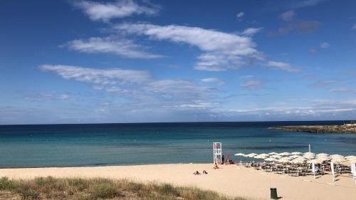 a beach with chairs and umbrellas and the ocean at B&B Alto Salento - Pool and Sun in Pulsano