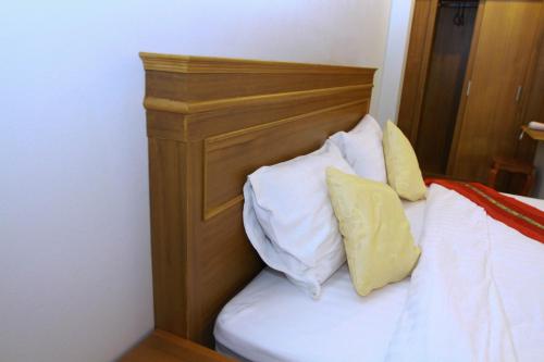 a bed with a wooden headboard and two pillows at Hugpua Hotel in Nan