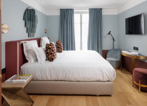 a bedroom with a large bed and a desk at Hôtel Parisianer in Paris