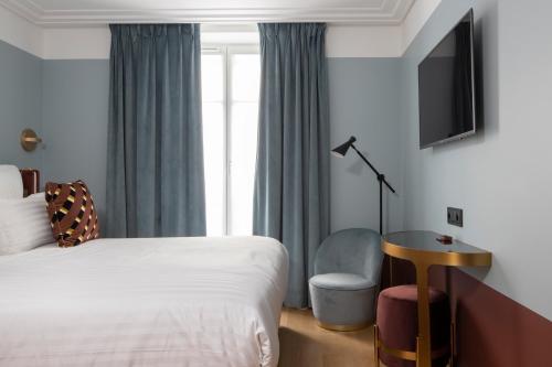 a hotel room with a bed and a desk and a tv at Hôtel Parisianer in Paris