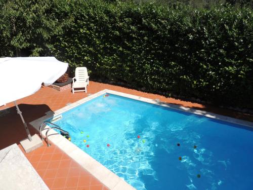 a large swimming pool with a chair and a umbrella at The Oaks in Spigno Saturnia