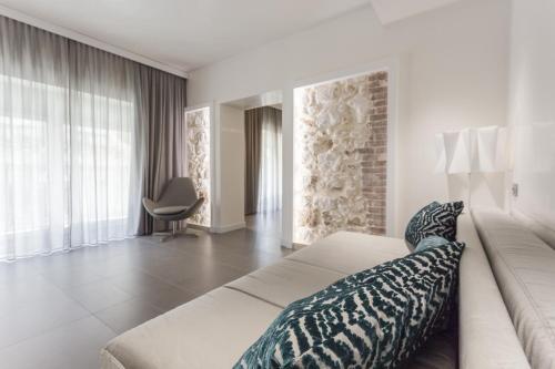 a bedroom with a large bed and a chair at Caportigia Boutique Hotel in Syracuse