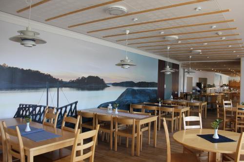 a restaurant with wooden tables and chairs and a large mural at Åh Stifts- & Konferensgård in Ljungskile