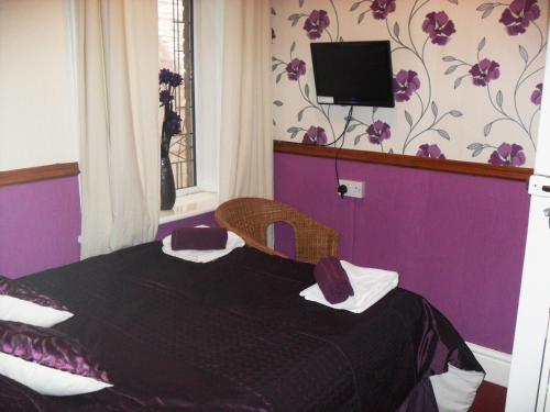 a room with a bed with a tv on the wall at Bradleys Hotel in Blackpool