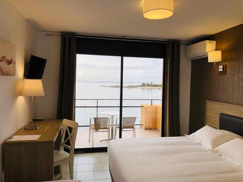 a hotel room with a bed and a desk and a window at Hôtel du Golfe in Sartène