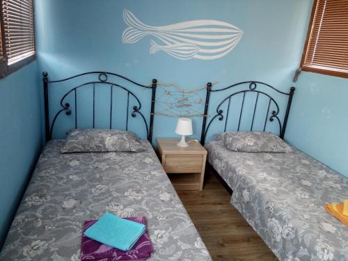 two twin beds in a room with a fish on the wall at Maisonette Endless Blue in Sinemorets