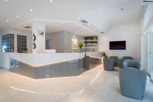 a lobby with a large white counter and chairs at Hotel Vega in Malcesine