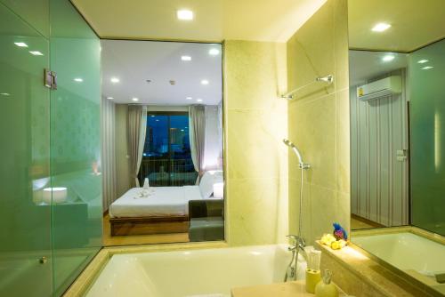 a bathroom with a bath tub and a bedroom at The Astra Suites in Chiang Mai