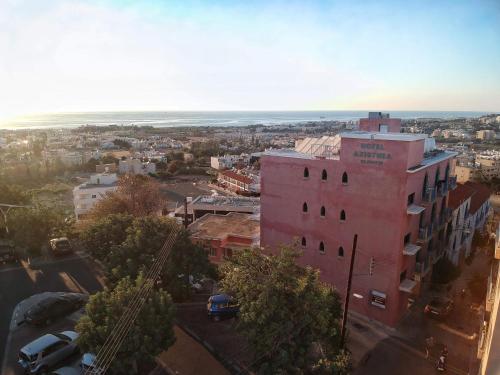 une vue aérienne sur une ville avec un bâtiment rose dans l'établissement Axiothea Hotel, à Paphos