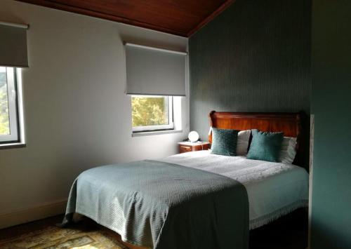 a bedroom with a bed with blue sheets and two windows at Quinta da Ermida - Turismo de Habitacao in Baião