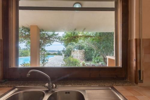 a kitchen sink with a window looking out at a pool at Villa Bellavista con piscina privata, vista mare vicino a Villasimius in Villasimius