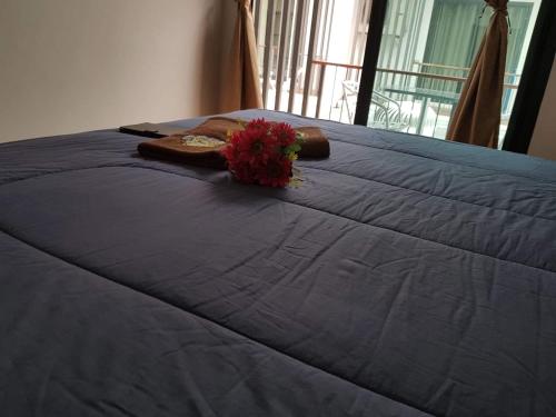 a blue bed with a vase of flowers on it at Amaretto Hostel in Surat Thani