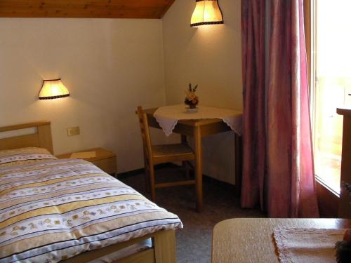 a bedroom with a bed and a table and a window at Appartamenti Suttru in Badia