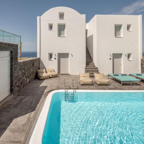 a villa with a swimming pool in front of a house at Elitoz Suites in Oia