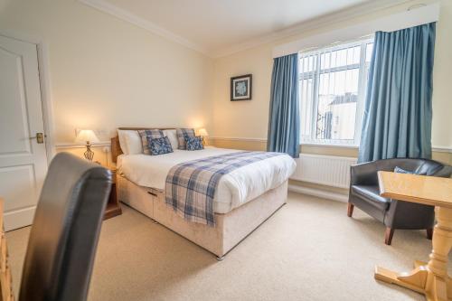 Schlafzimmer mit einem Bett, einem Schreibtisch und einem Fenster in der Unterkunft Atlantic Hotel in Tenby