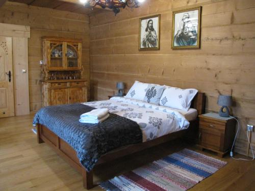 1 dormitorio con 1 cama y pared de madera en BoBak noclegi, en Chochołów