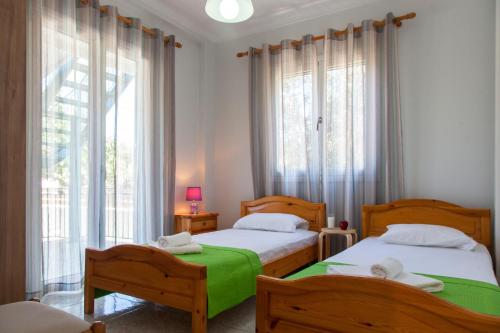 a bedroom with two beds and a large window at Agapanthus house in Lefkada