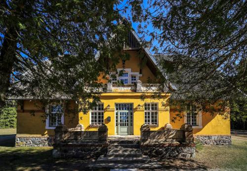 una casa gialla con finestre bianche e un albero di Bergervilla Boutique Guest House & SPA a Mežmuiža