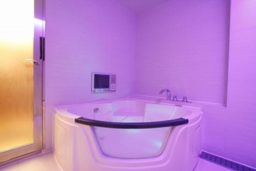 a large white bath tub in a bathroom with purple lighting at ホテルパシオン in Hamano