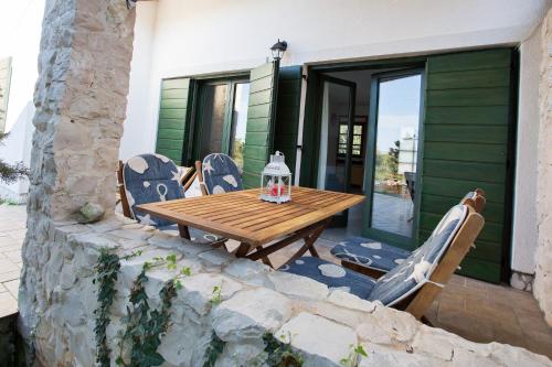 a wooden table and chairs on a patio at Studio apartman - MELLITUS in Molat