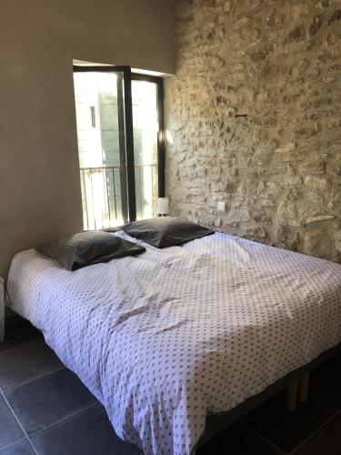 un lit dans une chambre avec un mur en pierre dans l'établissement 13 QUAI JEAN JAURES, à LʼIsle-sur-la-Sorgue