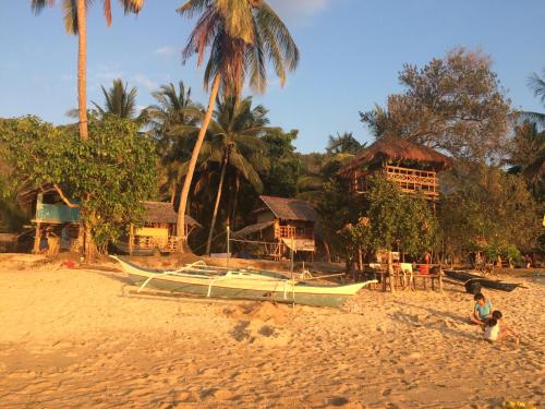 um barco sentado numa praia com casas ao fundo em Seafront Cottage Ocam Ocam Beach em Busuanga