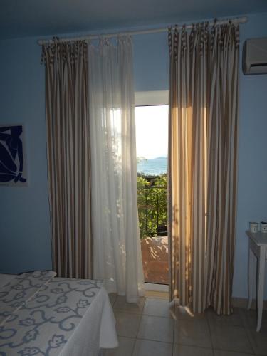 a bedroom with a bed and a large window at Palmina Mare Villa and Studios in Paralia Vrachou