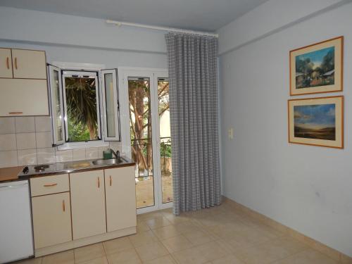 a kitchen with white cabinets and a sliding glass door at Palmina Mare Villa and Studios in Paralia Vrachou