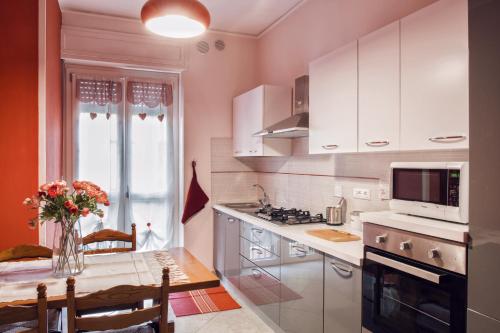 uma cozinha com armários brancos e uma mesa com um vaso de flores em La Casa di Giò em Asti