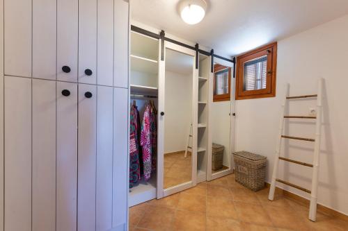a walk in closet with white cabinets and a mirror at Madalena's Summer House in Adamantas