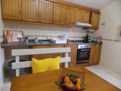 una cocina con una mesa con un bol de fruta. en Casa Moinho do Oeste - West Windmill Portugal en Moledo