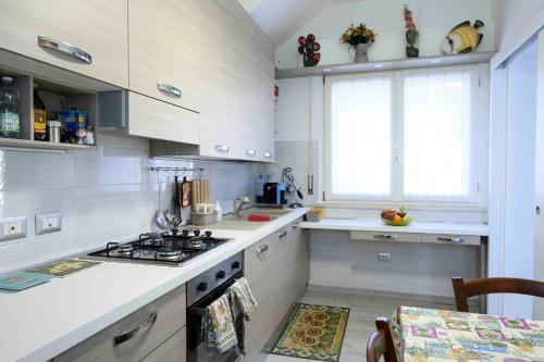 una cucina con armadi bianchi e piano cottura di intero appartamento con giardino e colazione Dario a Parma