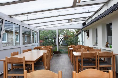 un comedor con mesas, sillas y ventanas en Kutscherhof Broock, en Broock