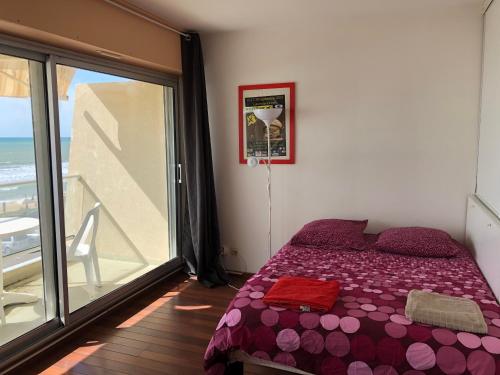 een slaapkamer met een bed en een groot raam bij Studio Face Ocean in Lacanau