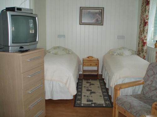 een kleine kamer met 2 bedden en een televisie bij Vadsø Apartment in Vadsø