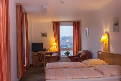 um quarto de hotel com duas camas e uma secretária e uma janela em TOTO's Gasthaus em Hattingen