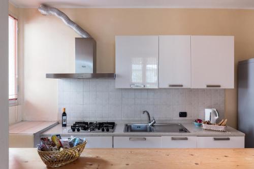 a kitchen with white cabinets and a sink and a basket at Residenza Santa Cecilia in San Vincenzo
