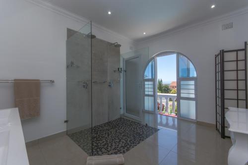 a bathroom with a shower and a glass door at Villa Capri Guesthouse Ballito in Ballito
