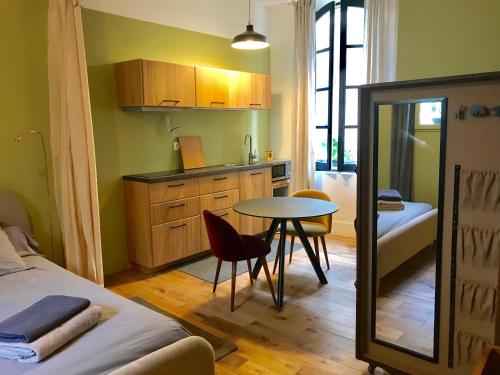 a room with a bed and a table and a kitchen at Studio de Charme à la Roquette in Arles