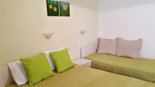 two beds in a room with green and pink pillows at Ikos Studios and Apartments in Patitiri